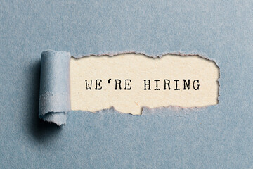 We are hiring message written on ripped torn cardboard paper on yellow background. Conceptual we...