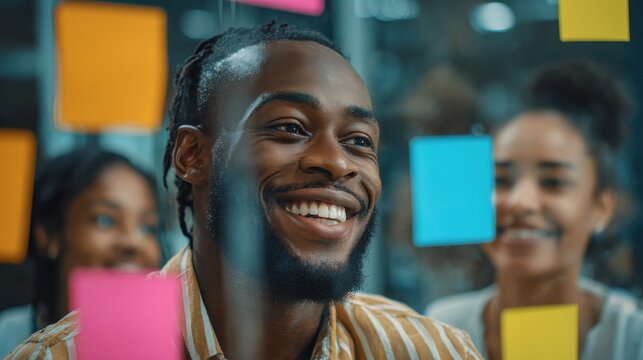 young african american manager and his smiling team brainstorming together with sticky notes on a glass wall during an office meeting no logos no brands ar 169