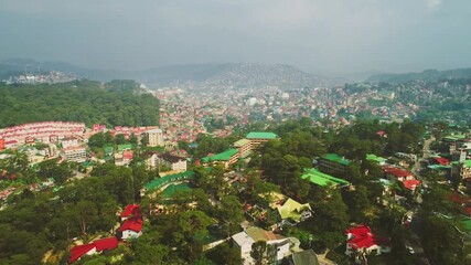 An aerial view of baguio city in the philippines shows buildings and trees