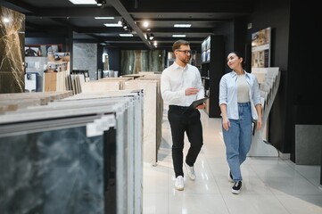 Salesman showing ceramic tiles to customer in store