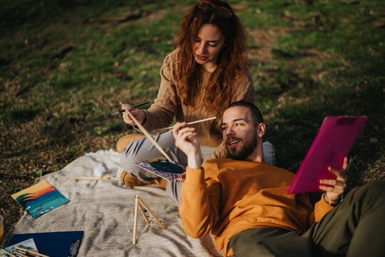 A couple spends quality time together painting outdoors, enjoying art and creativity in nature.