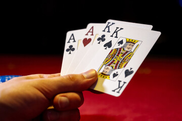 Obraz premium Close-up cards for playing poker on a gaming table in a casino against a background of chips. Background for a gaming business. Holding playing cards, playing poker at green table.