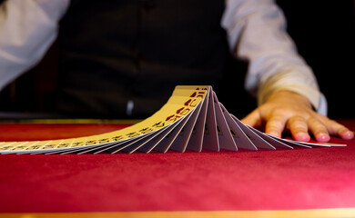 Croupier hands dealing cards on t blackjack poker table, gambling table with cards and chips. The croupier in the casino does a shuffle of cards. Person playing poker.