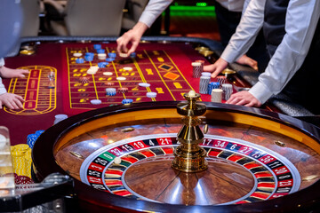 Croupier behind gambling table in a casino. Roulette wheel and croupier hand. A player in a casino, a lot of chips. Money and chips. A screensaver for a casino.