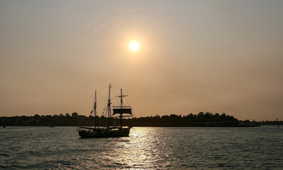 Silhouette  acht floating on the sea with beautiful sun set background in summer time, Sydney 
