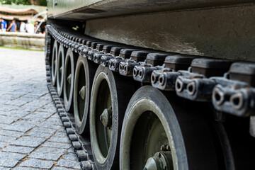 Close-up detail of military tank tracks and wheels on cobblestone ground, showcasing strength, engineering and armored vehicle design in warfare technology