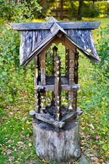 An old wooden bird feeder standing in the forest on a clear sunny day. Nature lake landscape ecology.