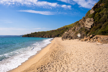 Obraz premium Sandy Irini beach in Greece with turquoise waters and rocky green hills.