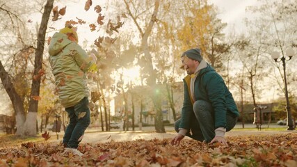 yellow dry leaves fly outdoors. happy child with father nature playing with yellow leaves. happy family park. chidhood dream. fun weekend kid with father sunset. girl daughter plays with dad autumn - Powered by Adobe