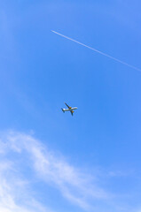 Airplane takes off into a blue sky with white clouds, Passenger plane aircraft flying across blue sky background, aircraft gaining altitude, view from below