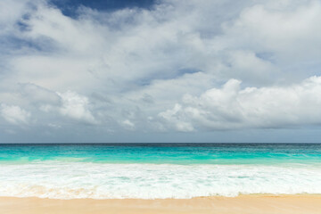 A tranquil beach scene with turquoise water, white sand, and gentle waves