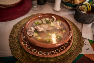 Rat broth, a typical dish from the state of Zacatecas, Mexico, accompanied by chopped vegetables and a whole field rat, served in a clay dish.
