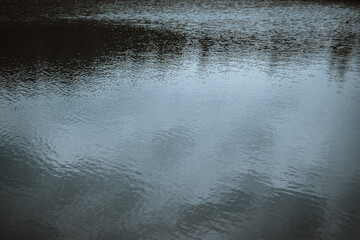 Abstract image depicting a dark blue water surface texture. The image features subtle ripples and reflections, creating a calming and serene atmosphere. 
