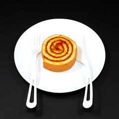 Roll cake with cutlery on black background closeup view, Flat lay food photography concept 