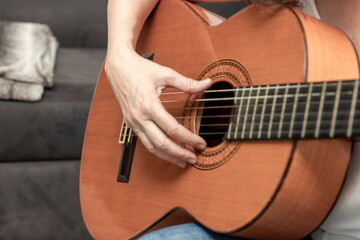 Close up of hand strumming acoustic classical wooden guitar strings