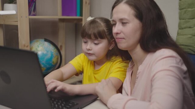 the child is making headway laptop vertual class. happy family. mother laughs hugging pupil daughter. parental assistance in children online education. caring mother is engaged with child on laptop