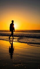 Silhouette of a person walks on a beach at sunset reflecting in the wet sand