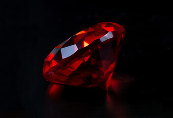 A polished red gemstone on a black background