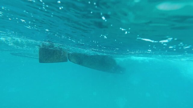 African man sailor in traditional wooden fishing boat in crystal clear turquoise water near Nungwi beach in Zanzibar. African tropical island tourism destination in Tanzania. 