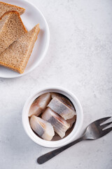 Herring slices in a white bowl on a white background