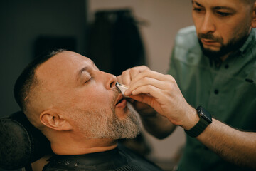 Male grooming, barbershop nose waxing for mature caucasian men