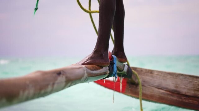 African man sailor on traditional wooden boat sail called dhow, near Nungwi beach in Zanzibar. African tropical island, tourism destination in Tanzania. 