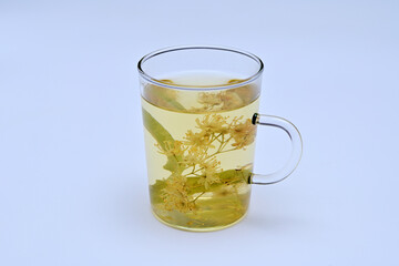 a cup with an infusion of linden flowers on a white background close-up