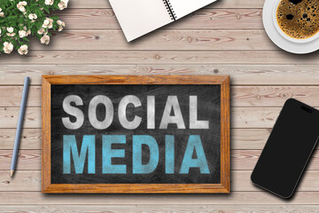 Social media written on framed Blackboard with  cup of coffee, notepad and pen on wooden table background