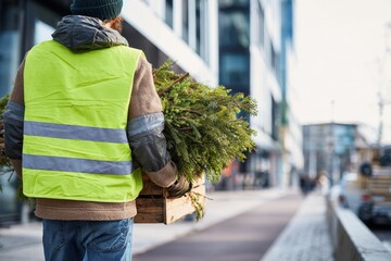 Worker Carry Christmas Tree For Disposal In City, Back View, Recycle Program, Modern Background, Waste Management, Seasonal Service, Holiday Season, Urban Landscape, Green Vest