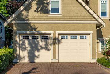 Garage door in luxury house with trees and nice landscape in Summer in Vancouver, Canada, North America. Day time on August 2025.
