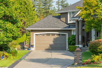 Garage door in luxury house with trees and nice landscape in Summer in Vancouver, Canada, North America. Day time on August 2025.