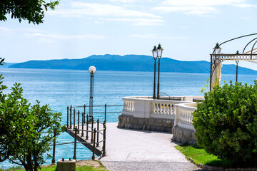 beautiful seaside promenade with Mediterranean vibes, balustrades, lampposts, and an island hill across the water. Opatija, Croatia, a famous coastal town on the Adriatic Sea
