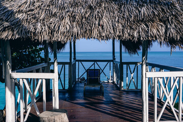 Wooden gazebo with thatched roof over water, perfect for relaxation.