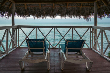 Two lounge chairs on a private deck with stunning ocean view at sunset.