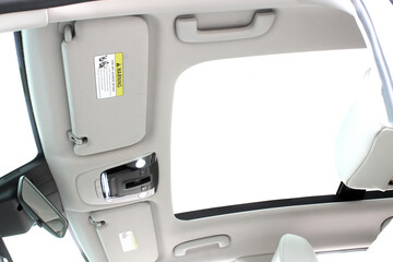 Car roof interior with panoramic sunroof, beige headliner, dual sun visors, overhead console with buttons, and grab handles for comfort and modern design.