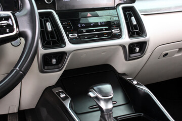 Close-up of modern car center console with gear shifter, climate control panel, dual digital...