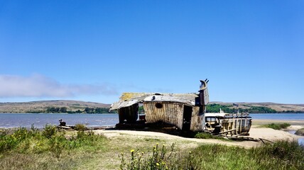 Stern of decayed wooden fishing boat wreck on sandy shoreline, Point Reyes, California
