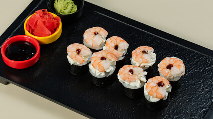 Sushi roll with soy sauce on black tray