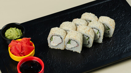 Sushi roll with soy sauce on black tray