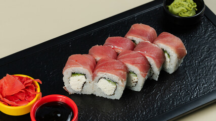 Sushi roll with soy sauce on black tray