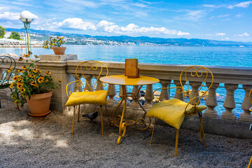 Cozy seaside cafe with yellow chairs, flowers, and stunning ocean view in opatia Croatia