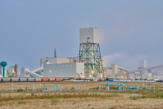 Industrial potash facility in Saskatchewan photographed at night with illuminated buildings and rail transport under a dark sky.