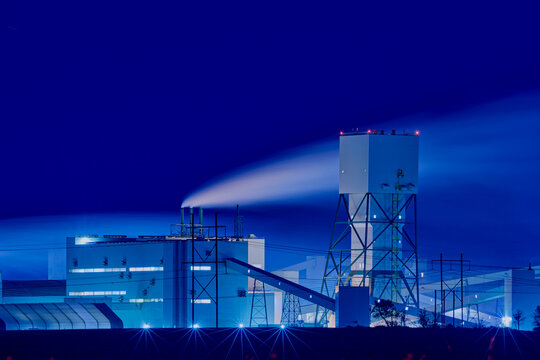 Potash mining and processing facility in Saskatchewan at night with illuminated structures and smoke under a dark sky.