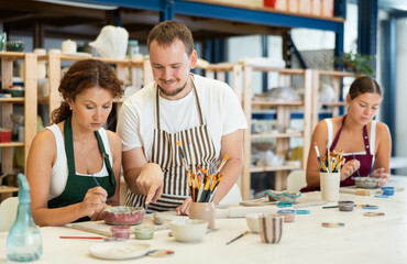 Experienced potter explains to students how to shape clay to make beautiful ceramic dishes