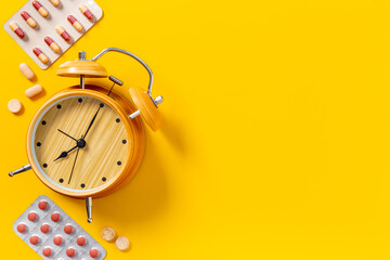 Medical treatment pills and vintage alarm clock, top view. Time to take medicine concept