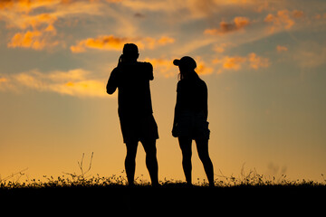 Silueta de pareja tomando fotos al atardecer 