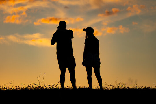 Silueta de pareja tomando fotos al atardecer 