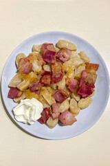 Traditional Poltava dumplings served with crispy cracklings, sautéed onions, and sour cream on a rustic plate.