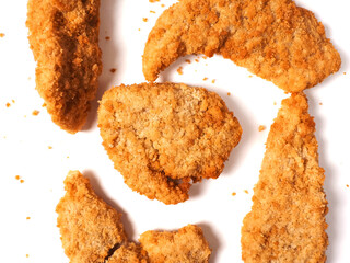 Uncooked chicken goujons or tenders in on white background. Popular classic chicken dish made from pieces of breast and breadcrumbs. Traditional ready to cook poultry product.