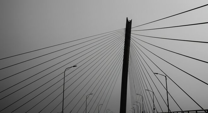 Dramatic cable-stayed bridge architecture against a vast, moody sky - Powered by Adobe